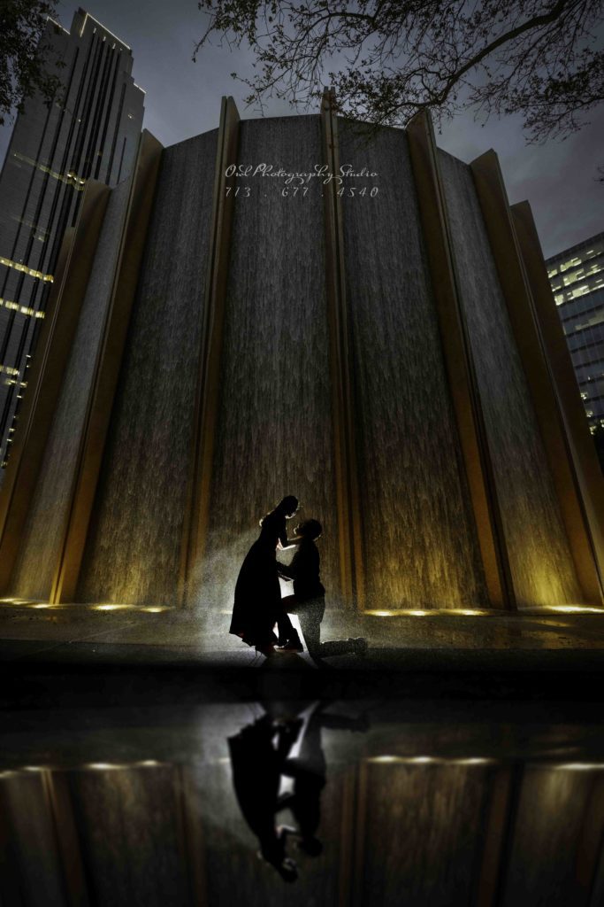 Couple proposing by illuminated fountain at night, Houston wedding photography