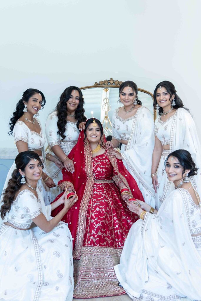 Bridesmaids in white surrounding bride in red wedding lehenga, Indian wedding photography Houston