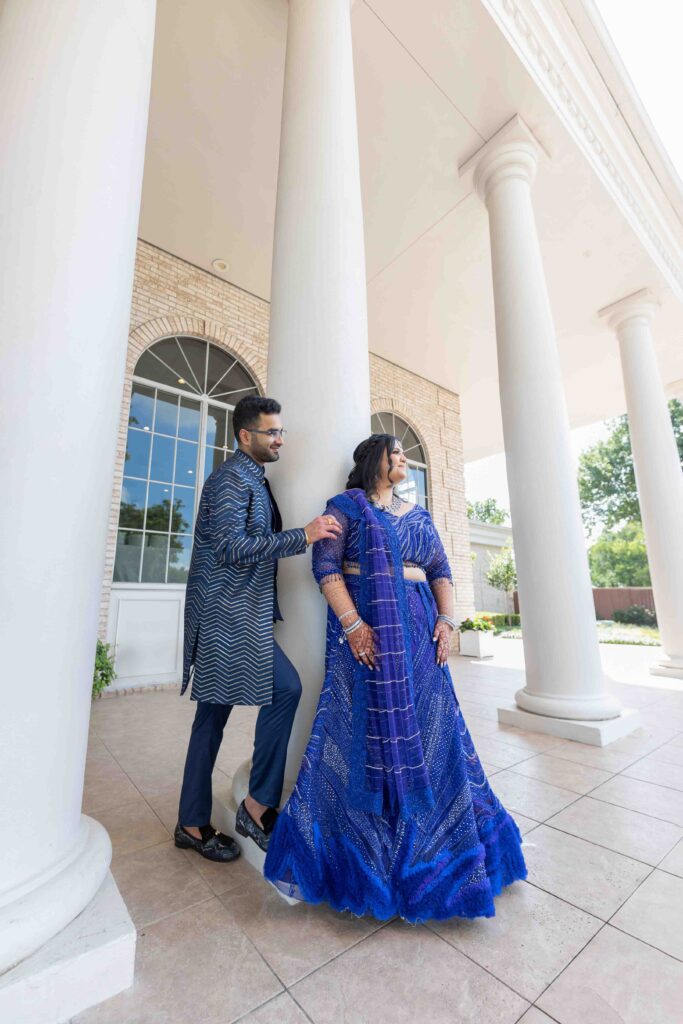 Wedding couple in traditional attire beside classical columns, Houston wedding photography