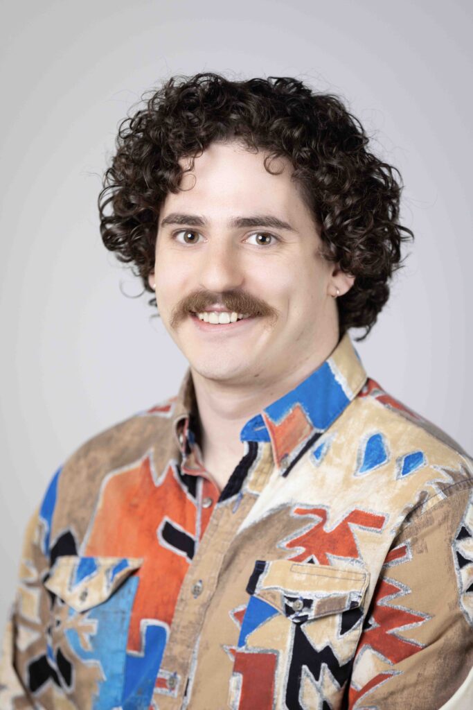Creative headshot of man with curly hair in colorful patterned jacket
