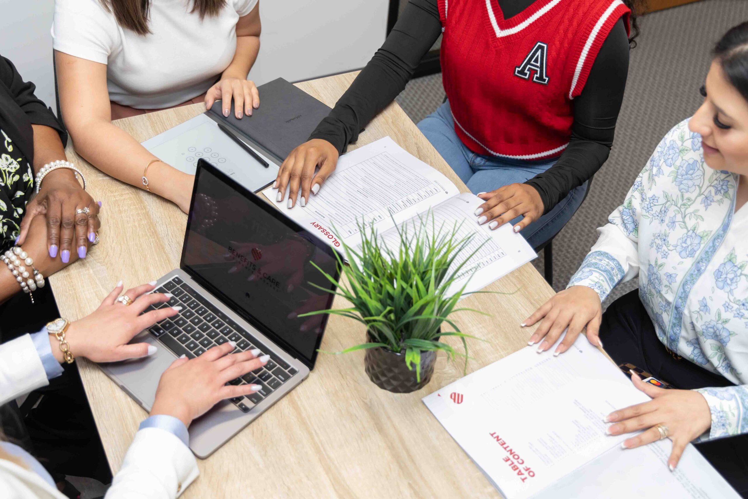 Team collaborating around office desk with laptops, Houston commercial photography